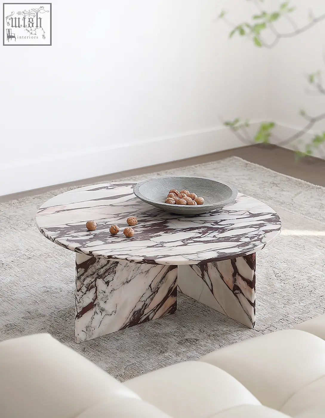 Round marble coffee table aiko with white and dark veined stone surface and three angular legs ideal for living rooms