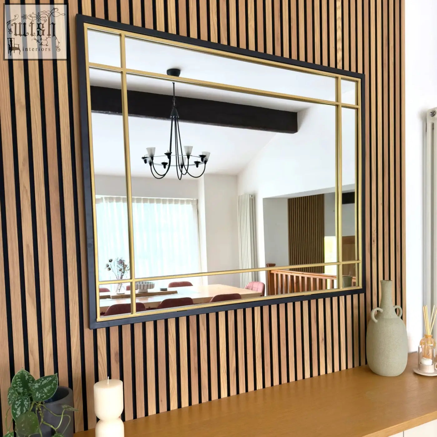 Aimi black metal frame window mirror with gold grid lines mounted on a wooden slat wall 95cm by 120cm