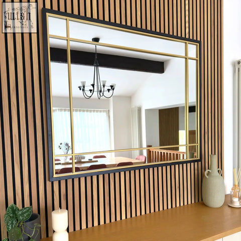 Aimi black metal frame window mirror with gold grid lines mounted on a wooden slat wall 95cm by 120cm