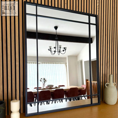 Aimi black metal rectangle window mirror with grid design reflecting a dining room interior, 95cm by 120cm