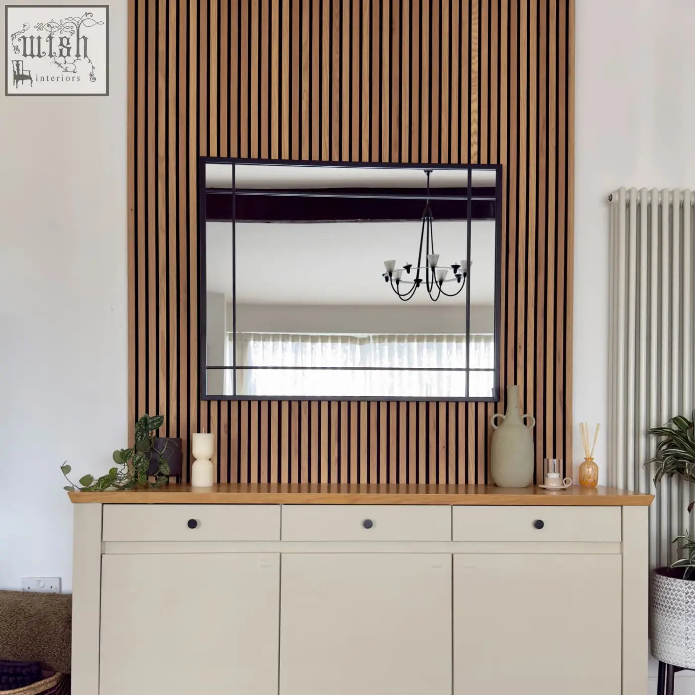 Aimi black metal rectangle window mirror with black frame mounted on wooden slat wall above cream cabinet