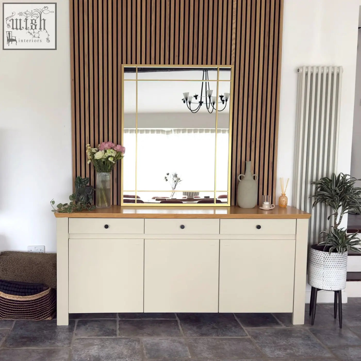 Cream-colored wooden console table with aimi gold metal rectangle window mirror mounted above it