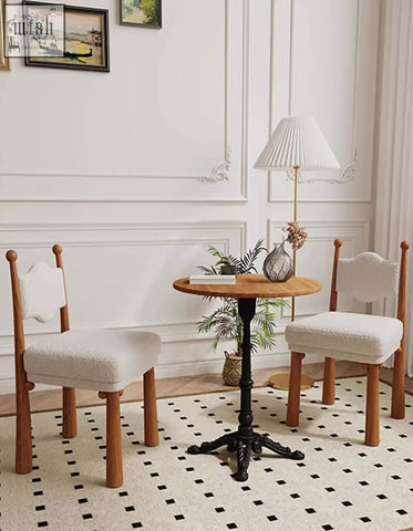 Wooden table with black metal base and round top paired with ainsley dining chair in cashmere fabric