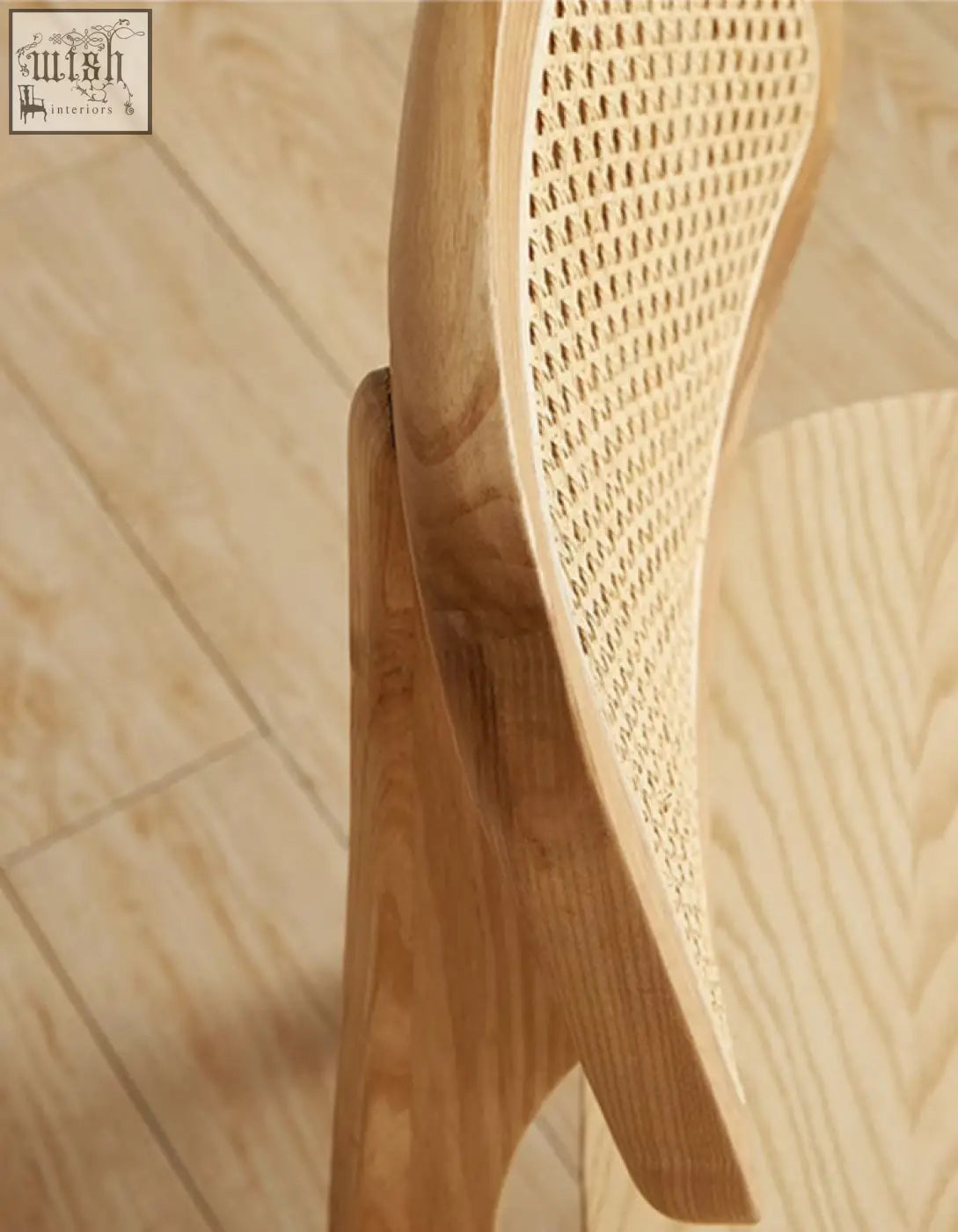 A light wood aislin rattan dining chair with a woven natural fiber backrest and minimalist frame perfect for dining
