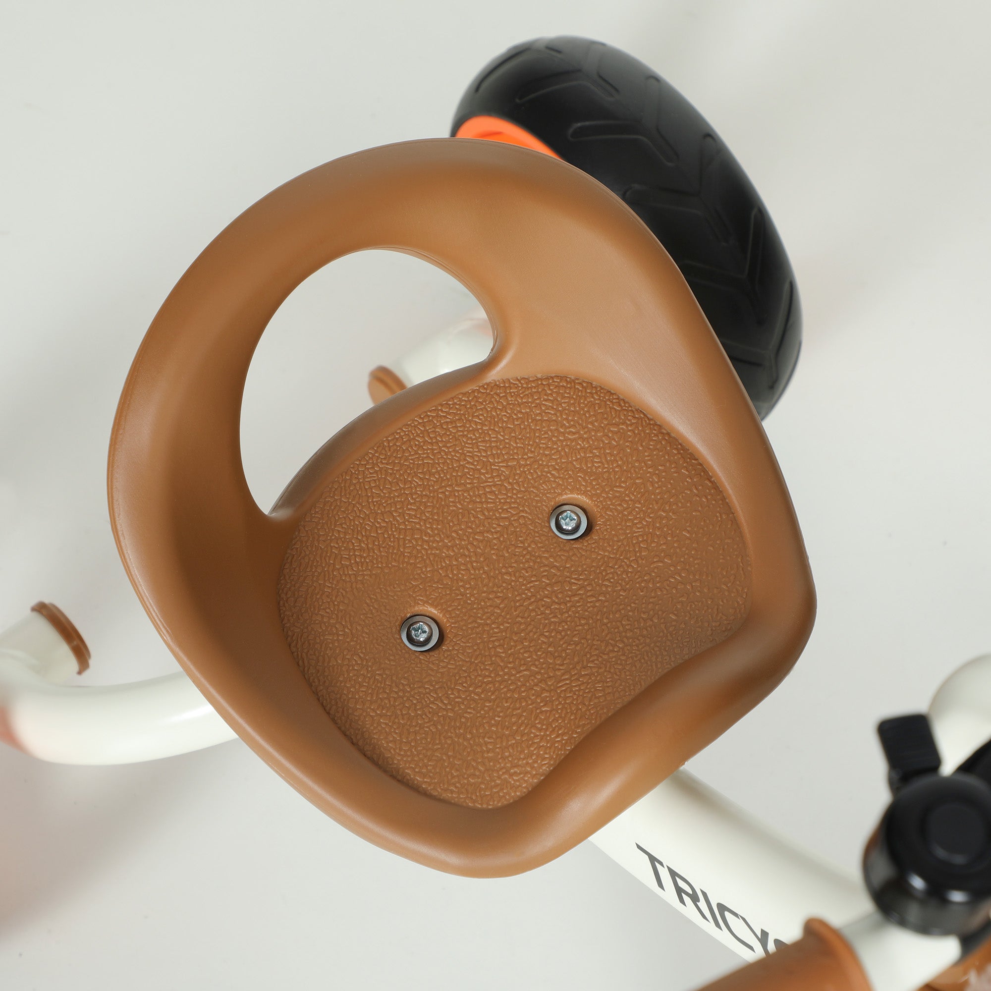 Brown plastic seat with textured grip and silver screws on the back of aiyaplay kids trike with eva wheels
