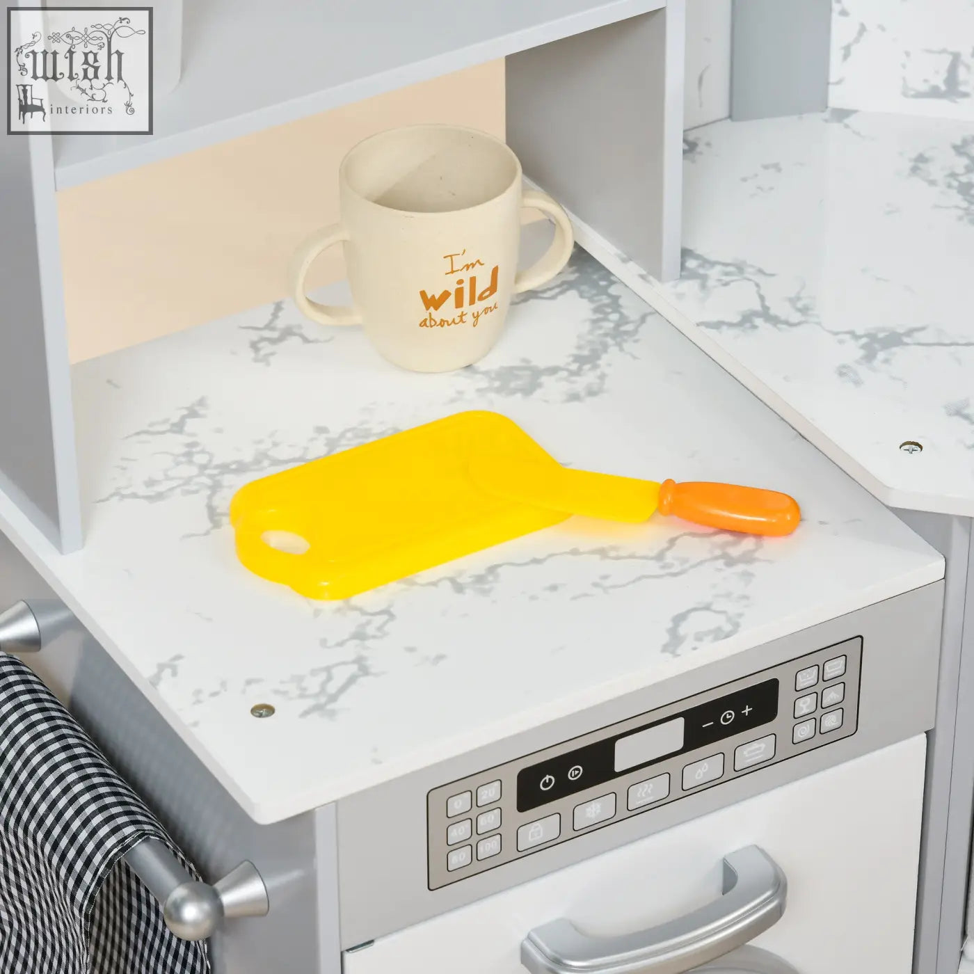 Bright yellow plastic cutting board with orange handle on marble countertop in aiyaplay kitchen playset with water dispenser