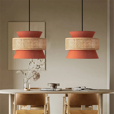 Two terracotta aka light pendant lights with woven rattan bands hang above a dining table