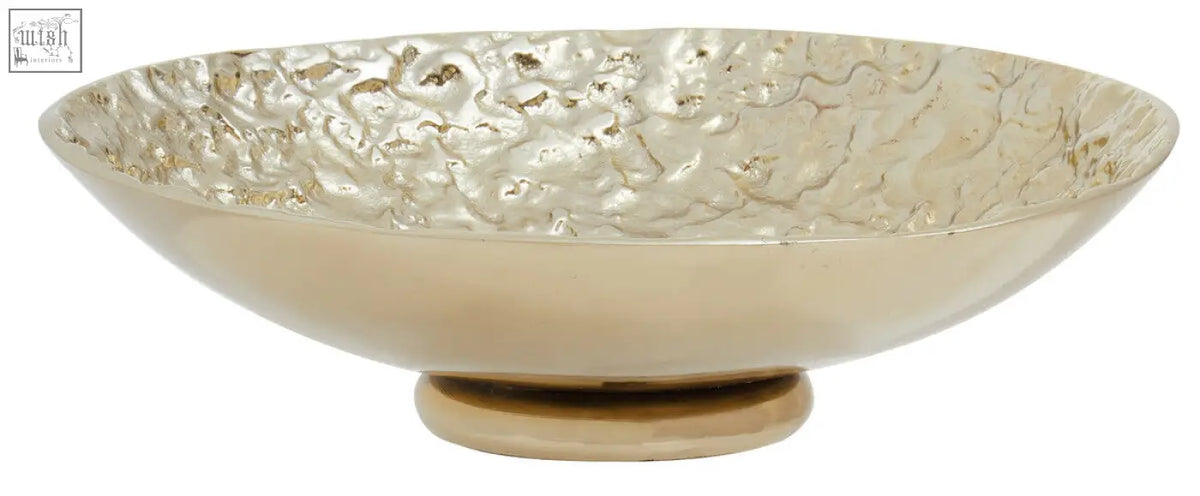A gold textured round metal bowl with hammered finish and small pedestal base perfect for decor or serving