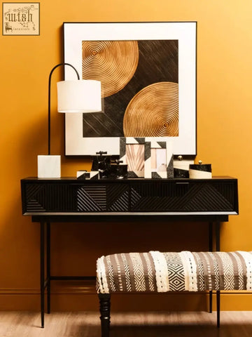Large black and gold trinket box with geometric carved front and slender metal legs for stylish storage