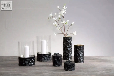Large black and gold trinket box with black textured cylindrical candle holders and clear glass tops with white candles