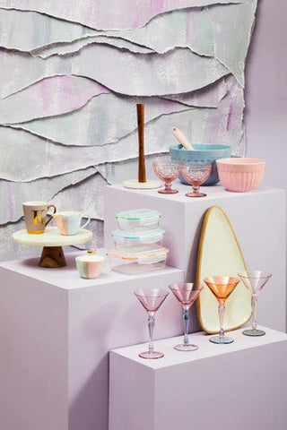 Pastel-colored glass cocktail glasses with slender stems next to alden melamine extra large blue mixing bowl