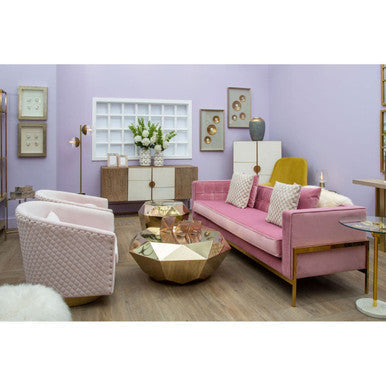 Pink velvet sofa with gold-tone metal legs and matching pillows next to allure champagne gold diamond cut end table