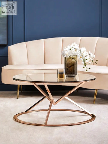 Rose gold coffee table with a clear glass top and geometric circular base perfect for stylish living rooms