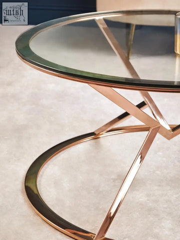 A modern allure corseted round rose gold coffee table with clear glass top and elegant gold coffee table legs