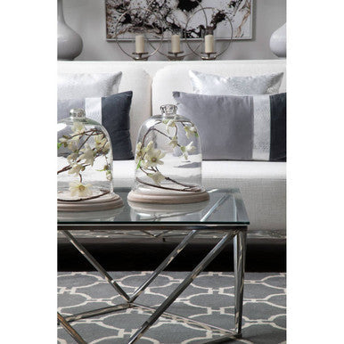 Two clear glass cloches with white flowers on wooden bases styled on the allure large twist coffee table
