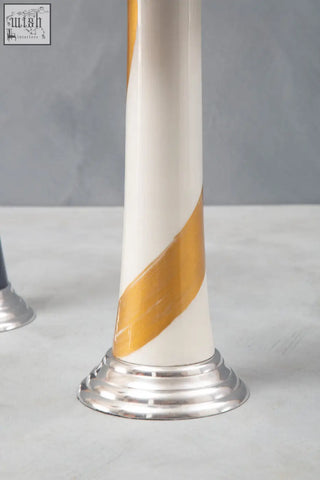 A sleek white and gold candle holder with striped ceramic body and polished silver metallic base perfect for gold candle decor