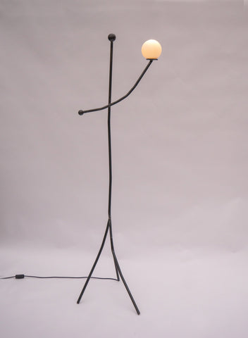 Black metal aluminium balancing act floor lamp with minimalist stick figure design and warm spherical glass bulb