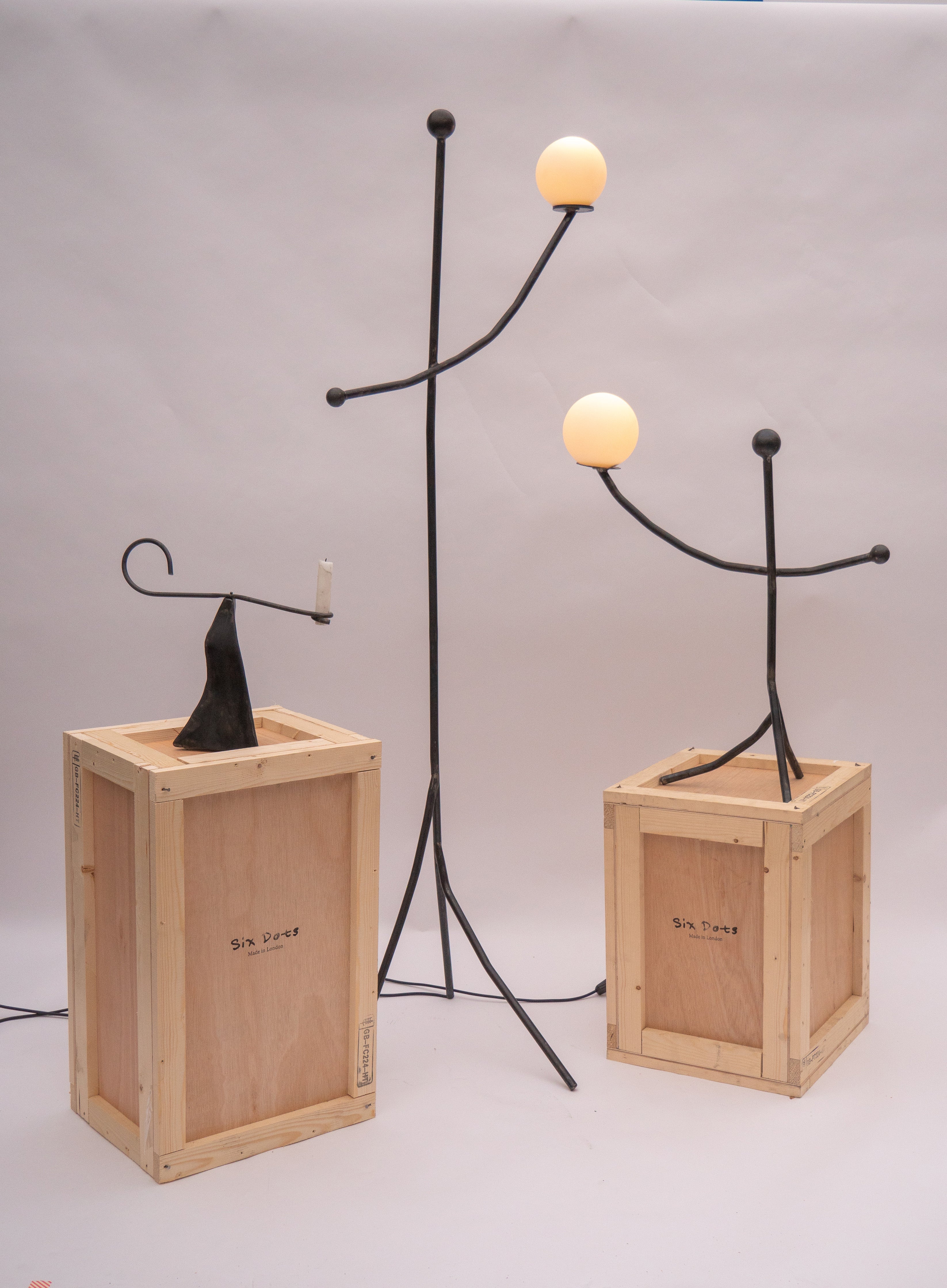 Black wrought iron aluminium balancing act floor lamp with two glowing spherical bulbs for ambient lighting