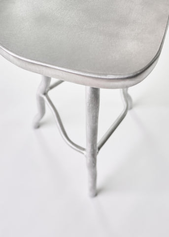 Silver metallic aluminium bar stool with smooth rounded seat and slender curved legs for stylish seating