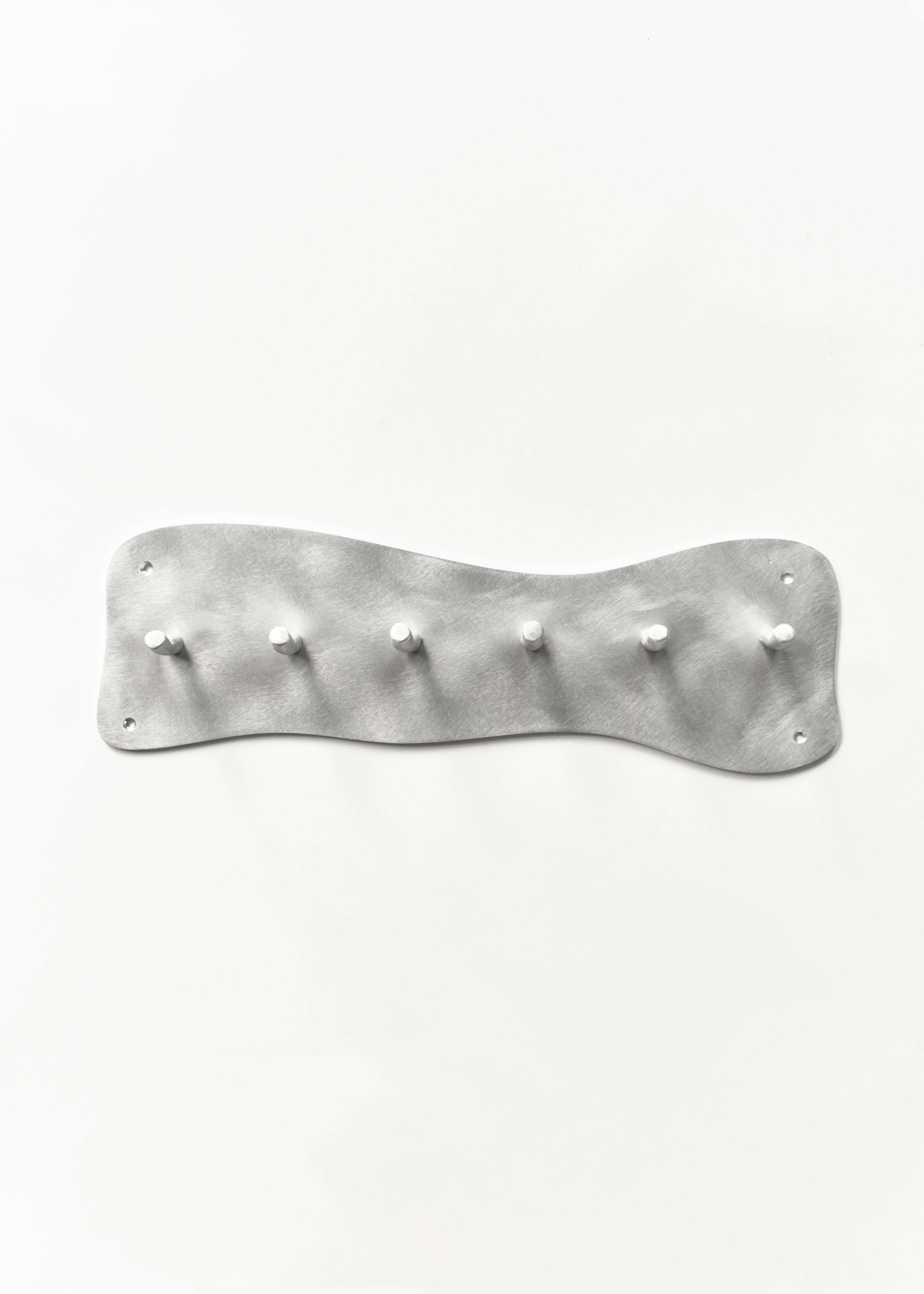 Silver metallic aluminium coat rack wall mounted with six hooks and a wavy textured surface