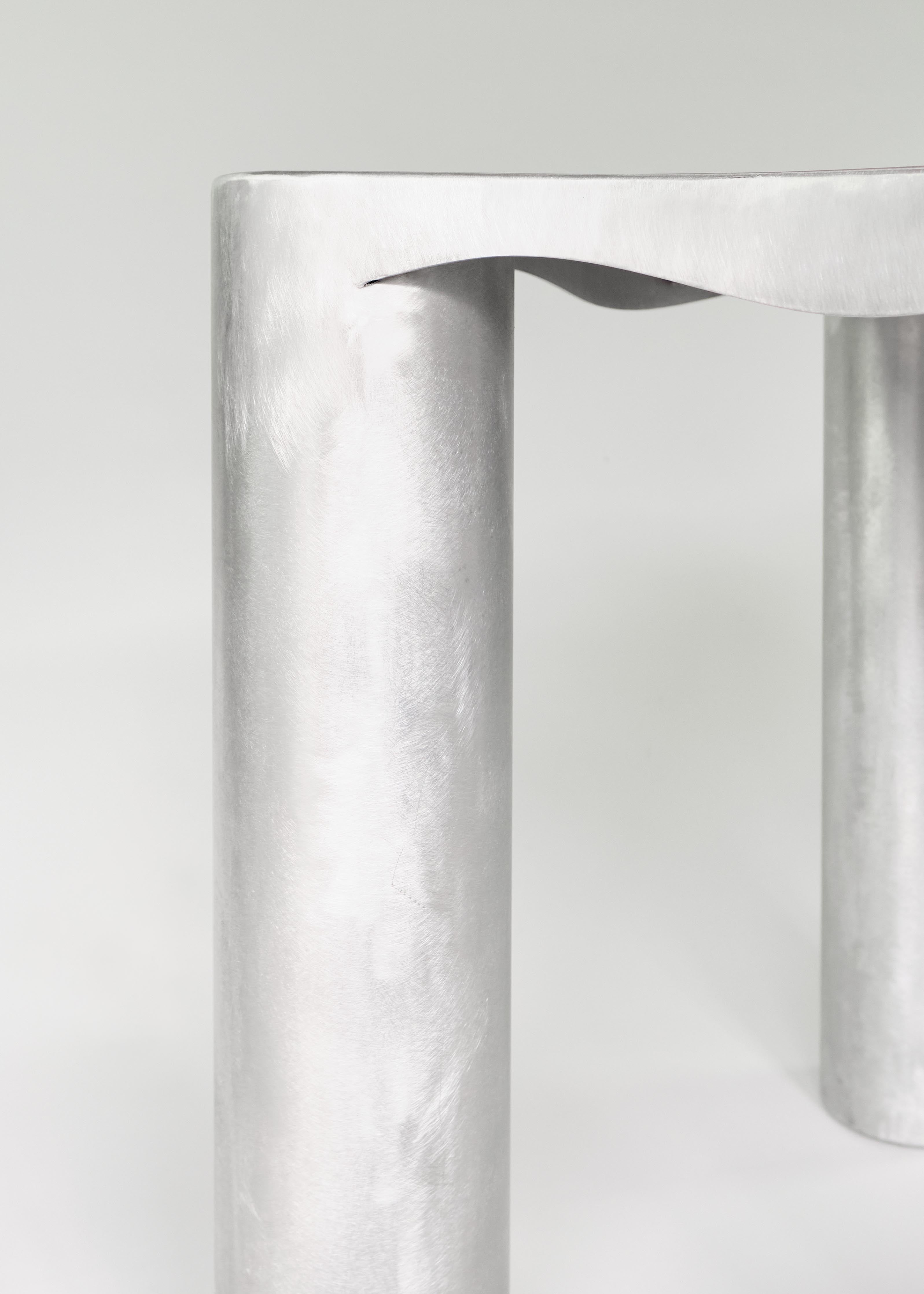 Silver metallic aluminium kitchen table with cylindrical legs and wavy sculpted top edge