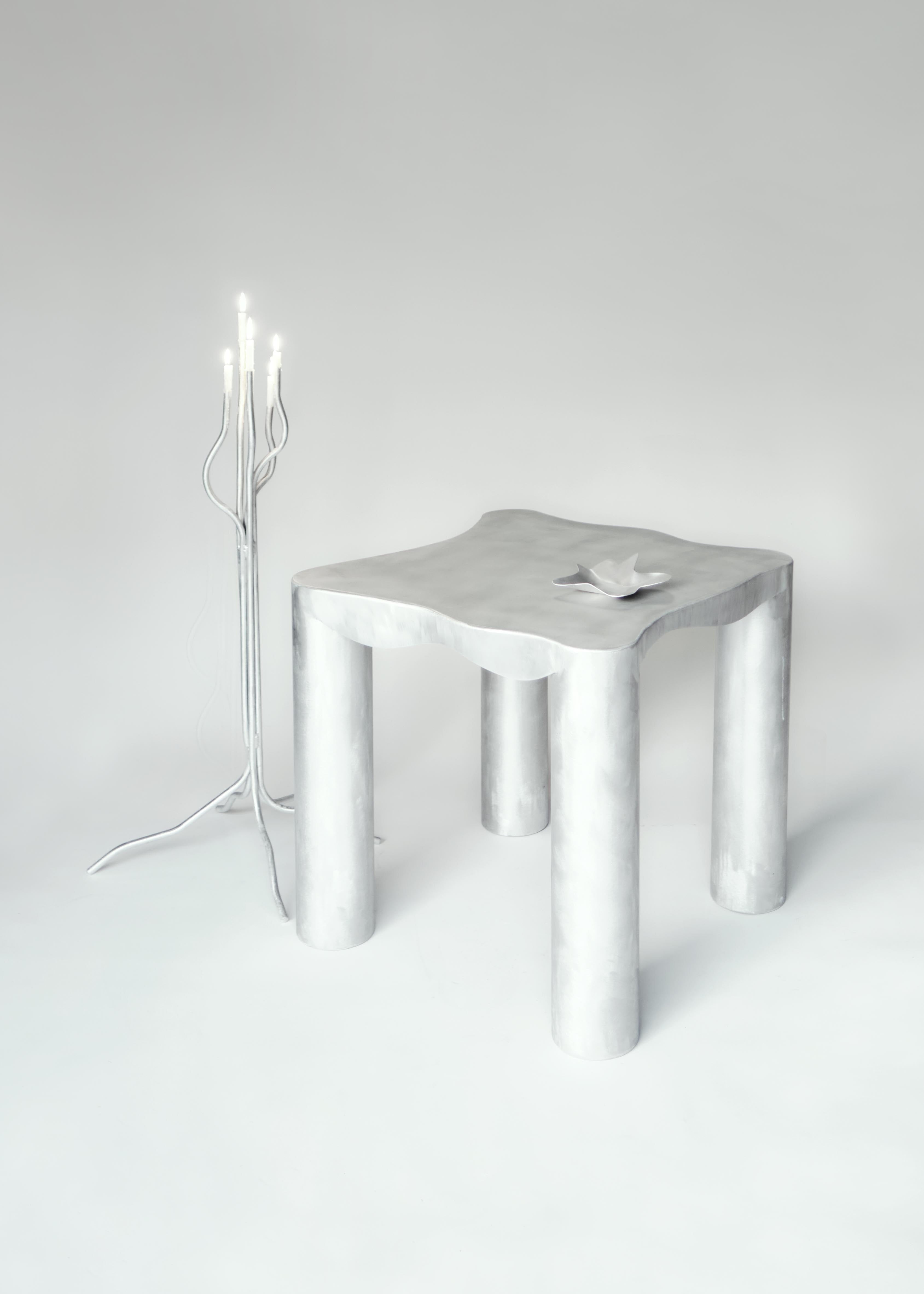 Silver metallic aluminium kitchen table with cylindrical legs and organic wavy surface design