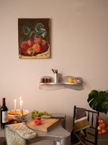 A sleek silver aluminium middle shelf with a curved modern design holds utensils and small kitchen items