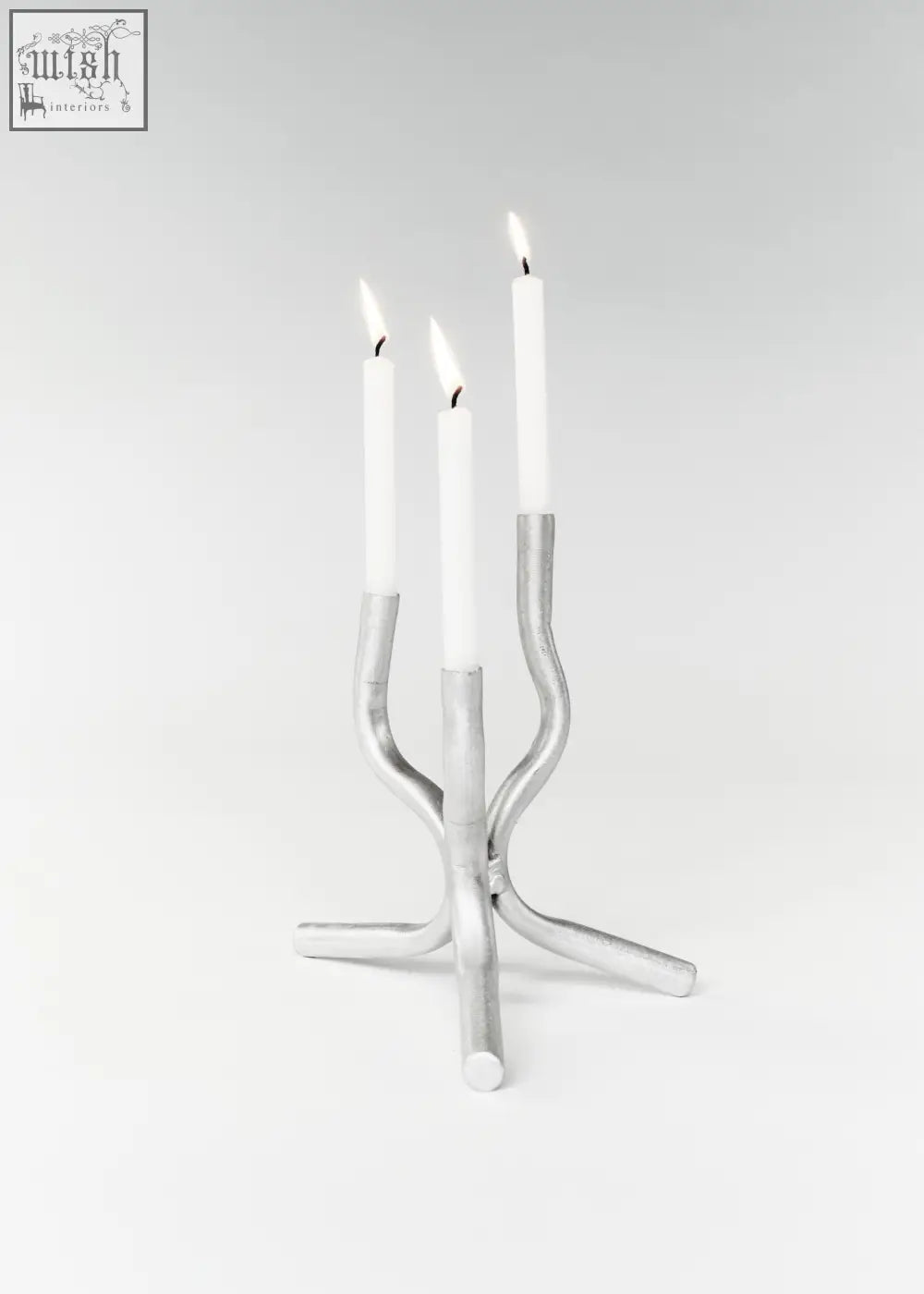 Silver metallic aluminium mini candelabra with three curved arms holding white taper candles