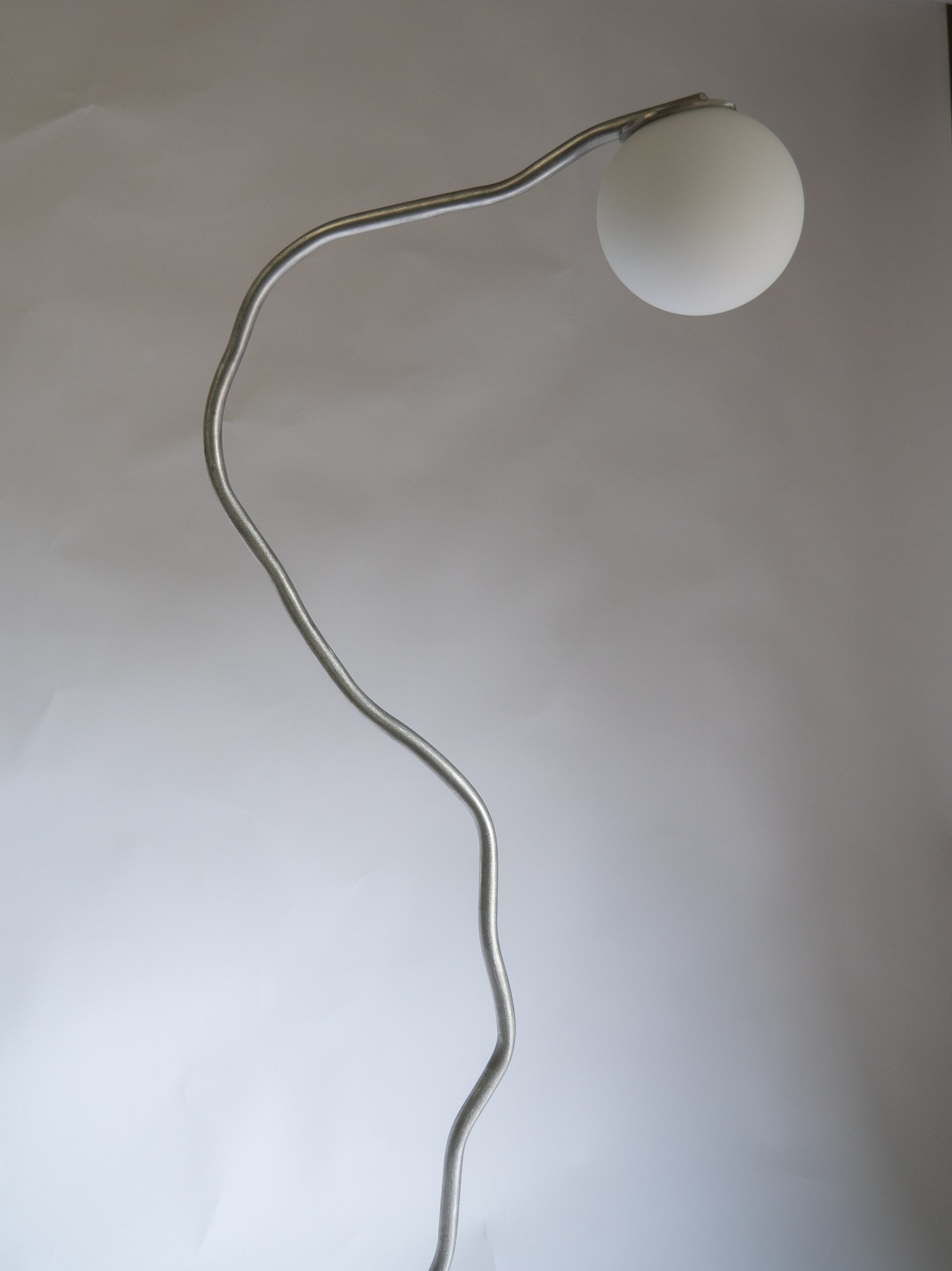 A sleek aluminium pea head floor lamp with a silver metal base and white spherical shade for modern lighting