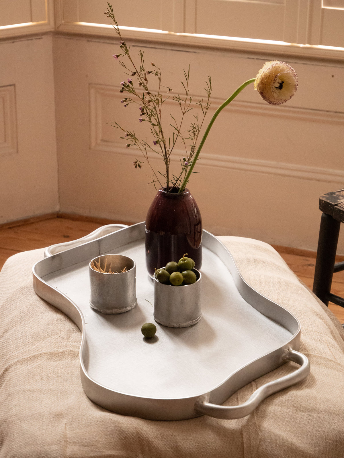 Silver-toned aluminium serving tray with sculptural design integrated handles and a slightly raised rim for easy carrying
