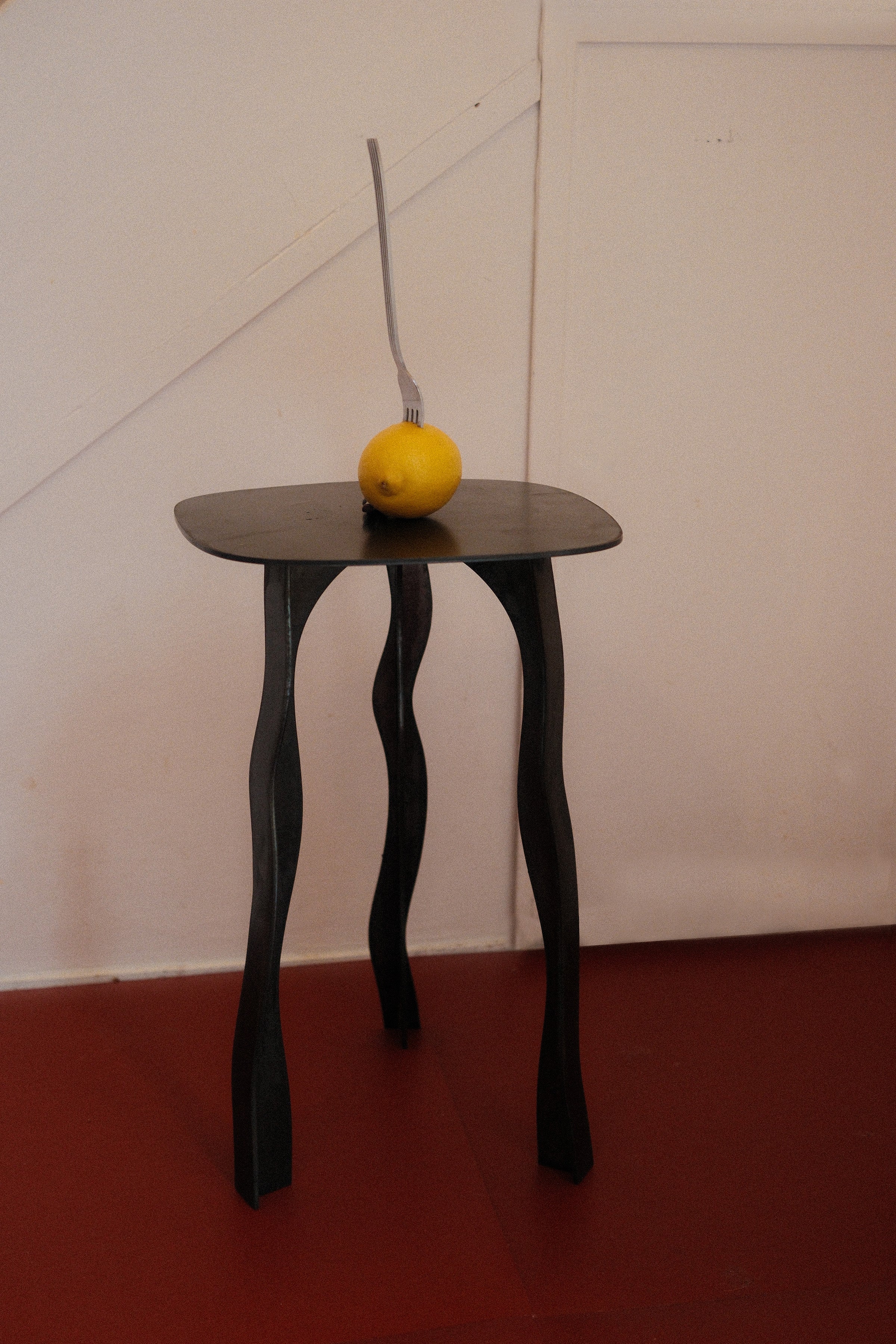 Black aluminium side table with wavy sculptural legs and smooth rounded top perfect for modern spaces