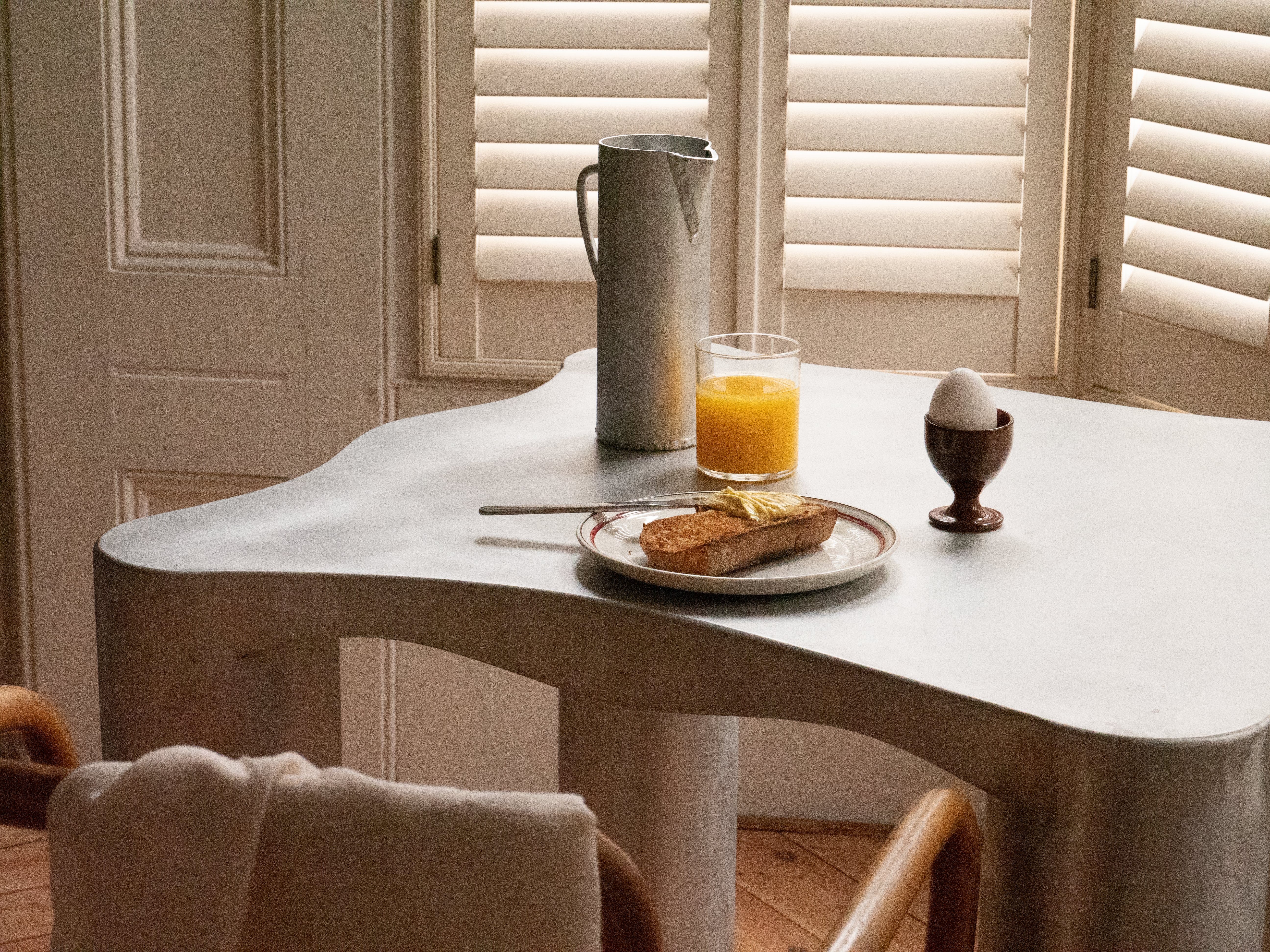 A sleek matte white aluminium jug with organic flowing curves and sturdy cylindrical legs perfect for any table setting