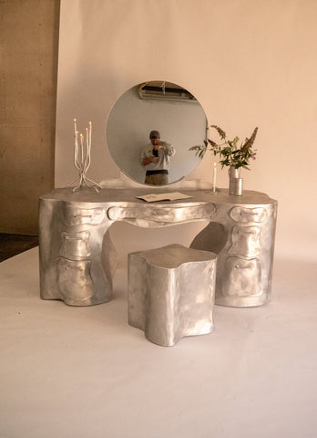 Silver aluminium vanity desk with sculpted organic bone-like contours and matching stool for stylish makeup setup