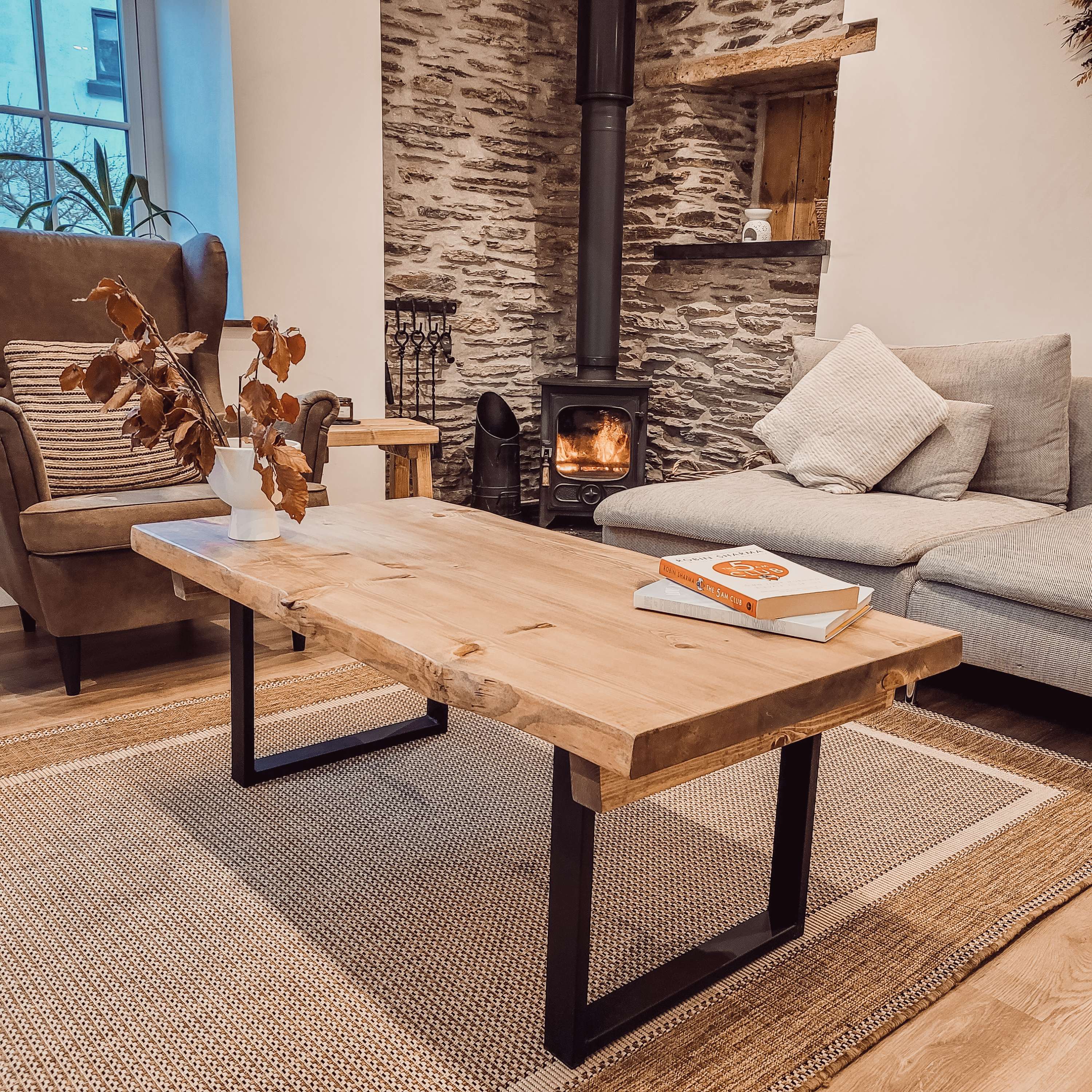 Light-colored rustic waney edge coffee table with black metal square legs perfect for stylish living spaces