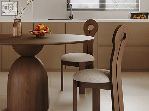 Dark wood amaia round pedestal dining table with bulbous base and two solid wood chairs with upholstered seats
