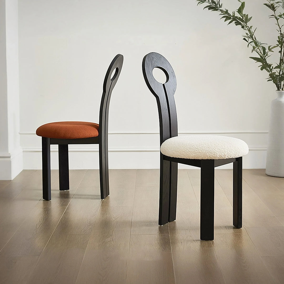 Black wooden amaris dining chair with oval backrests and boucle upholstered seats in warm orange and creamy white