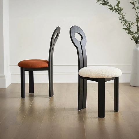 Black wooden amaris dining chair with oval backrests and boucle upholstered seats in warm orange and creamy white
