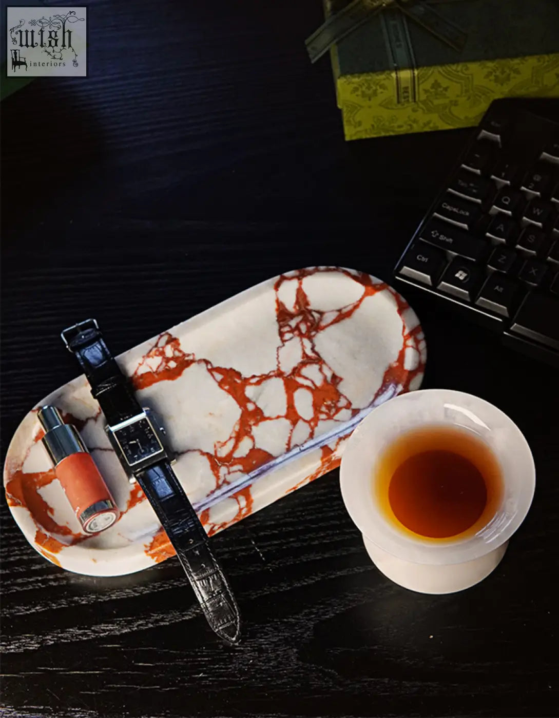 Amaryllis marble tray with white and orange pattern holding a black leather watch and orange lipstick with sleek design