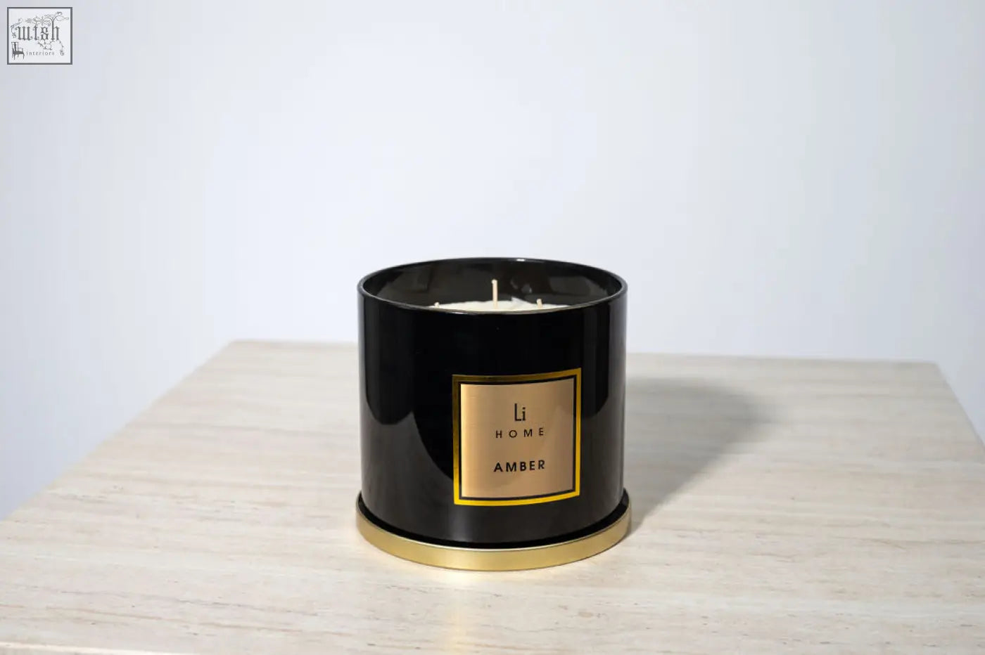Black cylindrical large candle with gold accents and li home amber label from amber 3 wick luxury candle collection