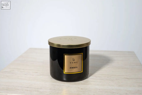 Black cylindrical amber candle with gold lid and li home label perfect for large candle collection display