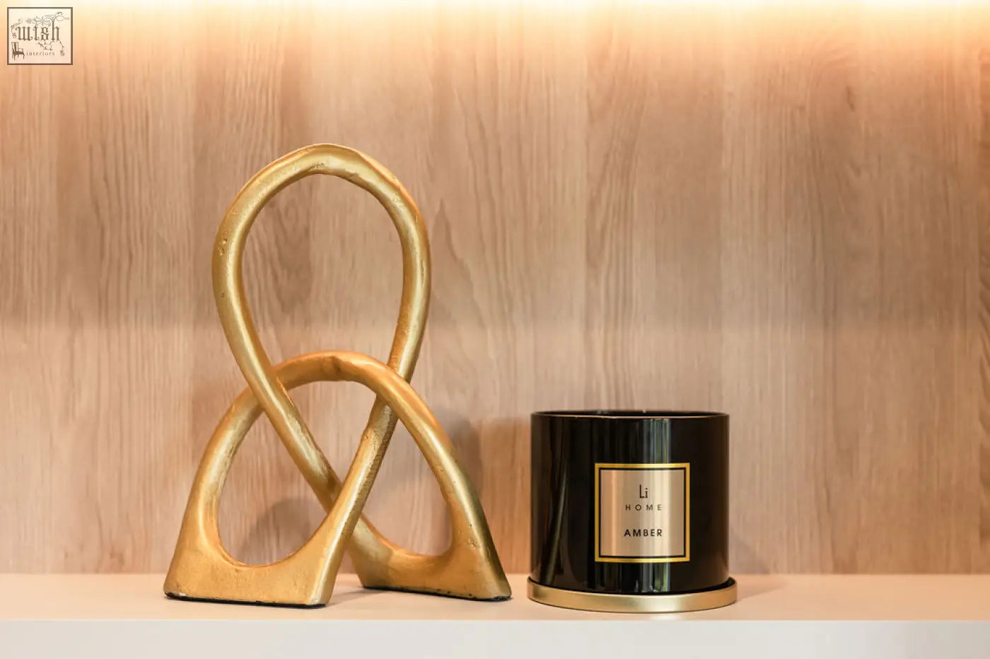 Gold-toned abstract sculpture with matte finish featuring intertwined loops for a large candle collection display