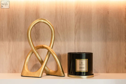 Gold-toned abstract sculpture with matte finish featuring intertwined loops for a large candle collection display
