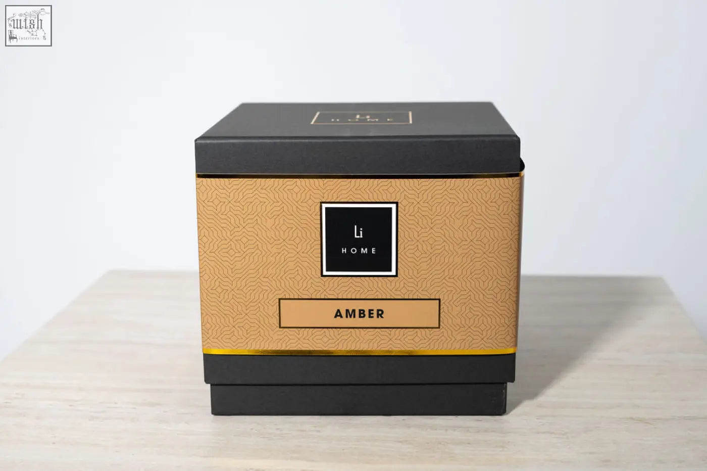 A sleek black and gold large candle from li home with a textured amber label in the amber 3 wick luxury candle collection