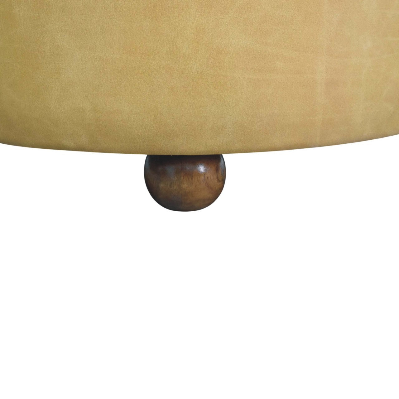 A round mustard yellow upholstered ottoman with dark brown wooden feet styled next to amber oak coffee table