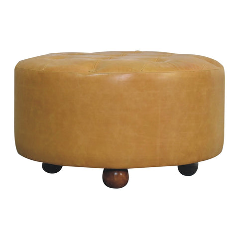 Tan leather tufted ottoman with rounded wooden legs serving as an amber oak leather coffee table centerpiece
