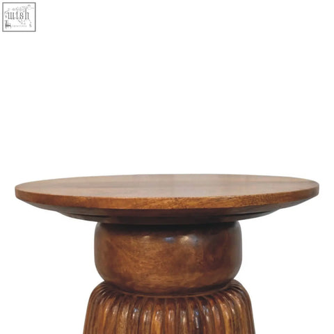 A round amber oak side table with a smooth top and intricately carved fluted wooden base in medium brown
