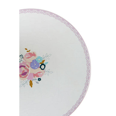 A delicate white ceramic floral pattern cake stand with soft pink and blue flowers along the curved edge