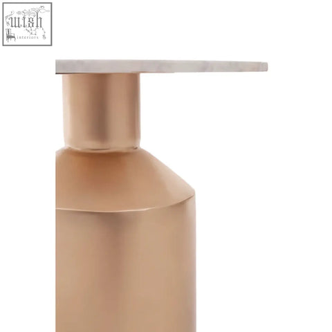 A sleek rose gold soap dispenser with a minimalist geometric design on an amira marble top gold base side table
