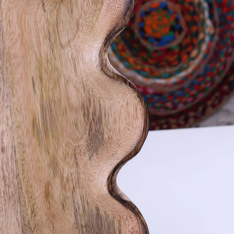 A light brown amrola mango wood serving dish with a smooth wavy edge perfect for wood serving
