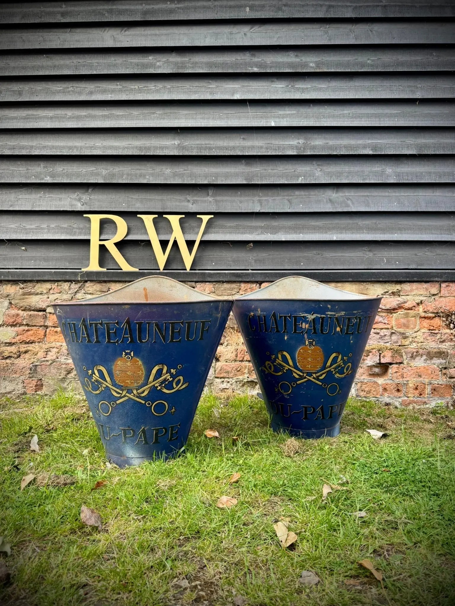 Two vintage blue metal garden bins with gold lettering and decorative insignia used as grape hod log baskets